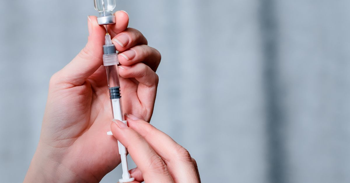medication dosage being prepared with a syringe from a vial.
