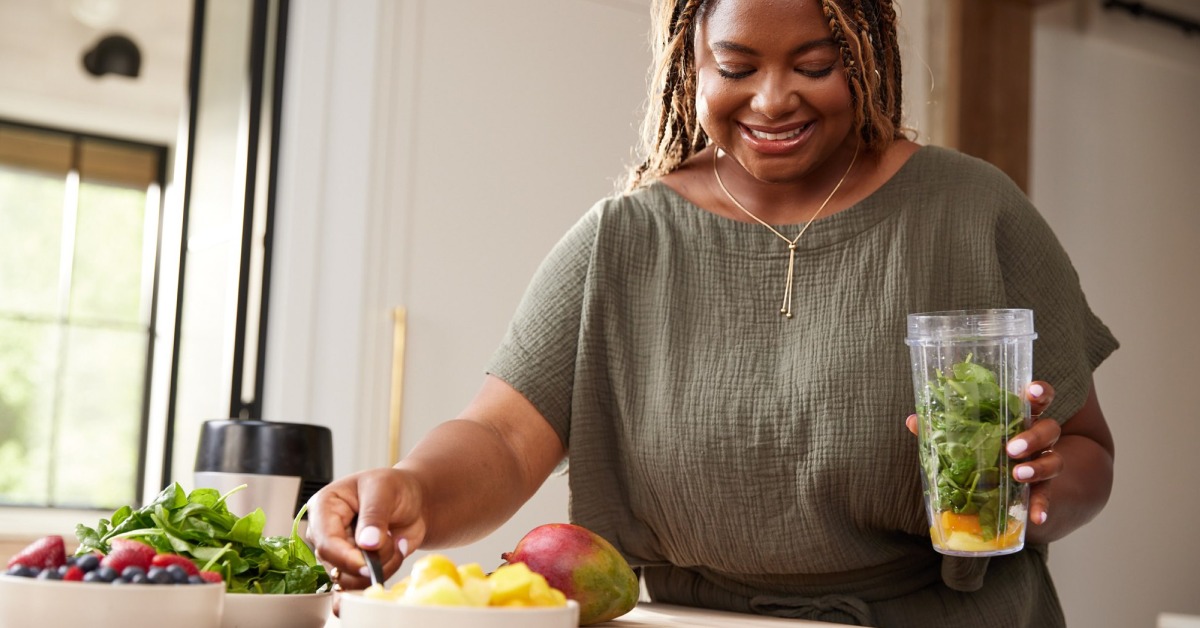 Woman making a healthy smoothie in the kitchen while maintaining a weight-loss routine on semaglutide.