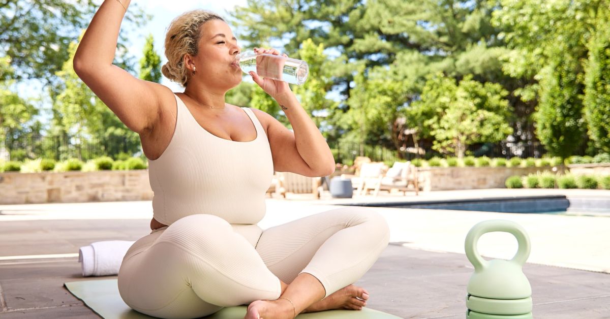 Woman in workout clothes sipping water, staying hydrated while maintaining SMART goals for a healthy lifestyle.